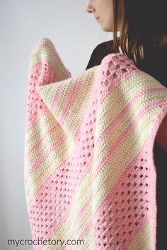 a woman holding a pink and white crocheted blanket