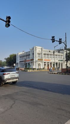 a car is driving down the street in front of an old building and traffic lights