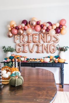 a dining room table with balloons and pumpkins on it, along with a sign that says friends giving