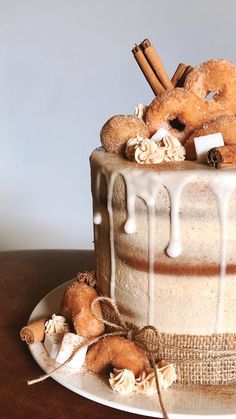 a frosted cake sitting on top of a wooden table next to cinnamon sticks and pretzels