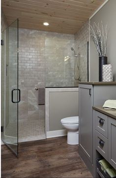 a bathroom with a toilet, sink and shower in it's stall area next to a wooden floor