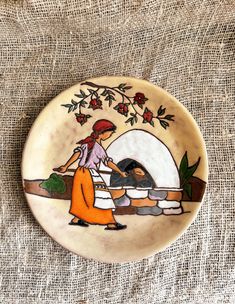 a ceramic plate with an image of a woman cooking in front of a stone oven