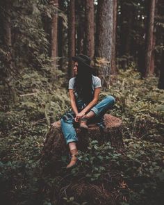 a person sitting on top of a log in the woods