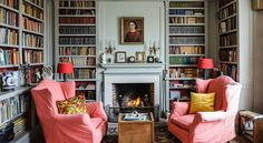 a living room with two chairs and a fire place in the middle of bookshelves