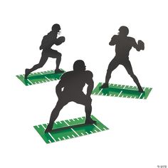 three silhouettes of football players on green mats