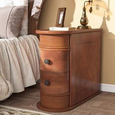 a bed room with a neatly made bed and a night stand on top of it