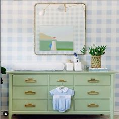 a baby's shirt is sitting on top of a dresser next to a mirror