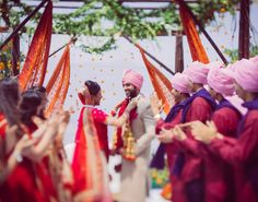 a man and woman in turbans standing next to each other at an outdoor ceremony