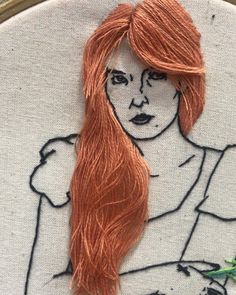 a close up of a embroidery on a hoop with a woman's face painted on it