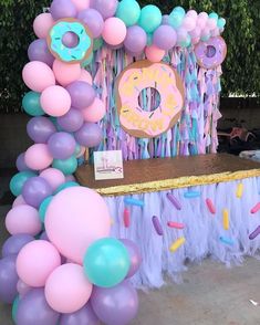 a table topped with balloons and doughnuts next to a sign that says donuts