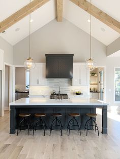 a large kitchen with an island and bar stools in it's center area