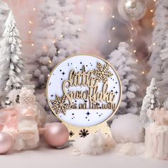 a white and gold christmas ornament sitting on top of snow covered trees