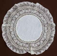 three white lace doily on a brown table cloth with an oval design in the center