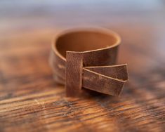 two pieces of brown leather sitting on top of a wooden table next to each other