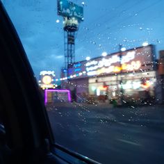 rain drops on the windshield of a car in front of a building with a neon sign