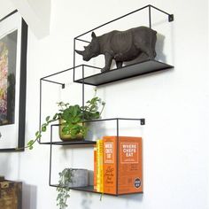 three shelves with plants and books on them in the shape of rhino's head