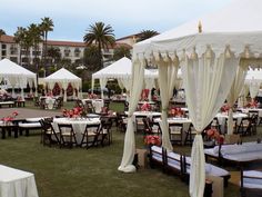 tables and chairs are set up for an outdoor event with white drapes on them