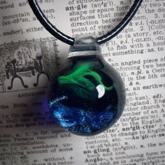 a glass bottle filled with blue and green liquid sitting on top of an open book