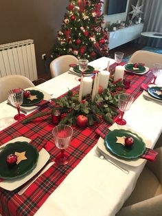 the table is set for christmas dinner with red and green decorations