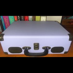 a white suit case sitting on top of a wooden table next to a bookshelf