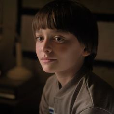 a close up of a person wearing a shirt and looking at the camera with a serious look on his face