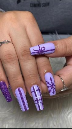 a woman's hand with purple and white nail polish on it, holding a ring