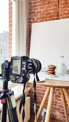 a camera is sitting on a tripod in front of a table with cookies and milk