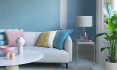 a living room with blue walls, white furniture and colorful rugs on the floor