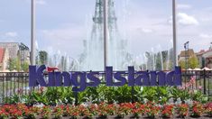 a sign that says kingsland in front of a fountain with flowers and trees around it