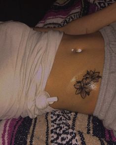 a woman laying on top of a bed with her stomach covered in white stuff and tattoos