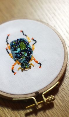 a close up of a embroidery on a wooden surface with a small object in the foreground