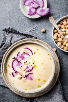 a bowl filled with soup next to two bowls of chick peas and radishes