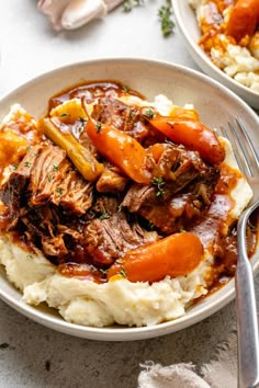 a plate with mashed potatoes, meat and carrots on it next to a fork