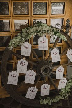 a wagon wheel with tags attached to it and greenery around the wheels is shown