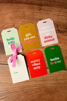 four christmas gift tags with pink ribbon on wooden table next to each other and the tag says merry, you are sleeping