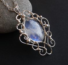 This stunningly elegant pendant necklace is handcrafted from sterling silver and a gorgeous rainbow moonstone cabochon, with lovely flashes of blue color. Pendant comes with an Italian made .925 sterling silver chain with lobster clasp (see photos) in your choice of length. Generously sized bail allows you to swap out different chain styles, if desired. One of a kind pendant measures approximately 2 inches long by 1.25 inches wide, and will come beautifully gift boxed, as shown in last photo. Sh Elegant Oval Labradorite Pendant Jewelry, Handmade Moonstone Jewelry In White Gold, Handmade White Gold Moonstone Jewelry, Elegant Hand Forged Moonstone Jewelry, Elegant Silver Labradorite Jewelry, Oval Moonstone Wire Wrapped Jewelry, Moonstone Pendant Necklace, Rainbow Moonstone Pendant, Sterling Silver Wire Wrap