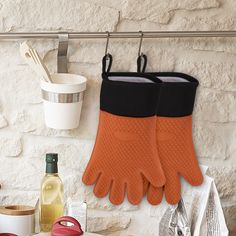 two oven mitts hanging on a wall next to other kitchen items and utensils