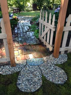 an outdoor garden area with stone and glass stepping stones on the ground, along with a white picket fence