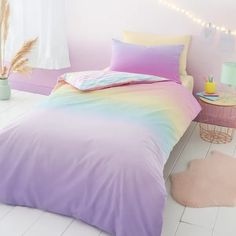 there is a bed with a rainbow comforter and pillows on the floor in this room