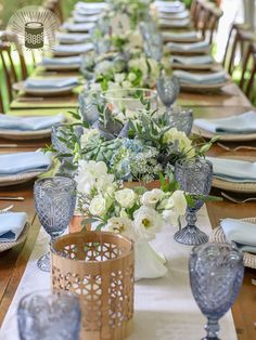 the table is set with blue and white dishes, napkins, and vases