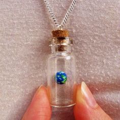 "18'' Curb Sterling Silver Chain 40mm X 15mm / 1.6\" X 0.6\" Glass bottle and Cork Earth made of fimo, suspended in a mini glass bottle with cork, on a sterling silver chain. I've been making and selling my own Jewellery since 2000 when, at 10 years old, I set up my first stall selling hand-made jewellery and accessories. I earnt my first income, and from this bought myself a micro scooter- which I still use to this day! For years I've been fascinated with the beauty and realities of space which Glass Dome Jewelry, Solar System Necklace, Tiny Jars, Glass Bottles With Corks, Mini Glass Bottles, Mini Lamp, Bottle Corks, Bottle Charms, Bottle Necklace