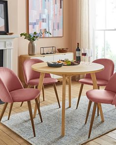 a dining room table with pink chairs around it