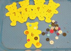 some buttons are laying on a tray with teddy bears and letters that spell out numbers