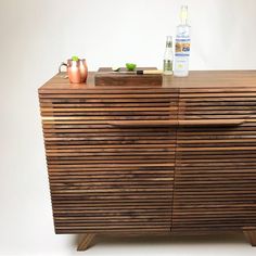 a wooden cabinet with two vases on top of it