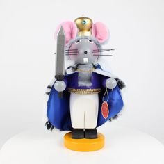 a mouse figurine holding a knife and wearing a blue outfit with gold accents