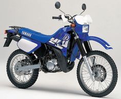 a blue and white yamaha dirt bike parked in front of a gray background with the number 24 on it