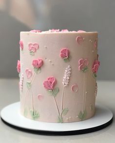 a close up of a cake on a plate with pink frosting flowers and leaves