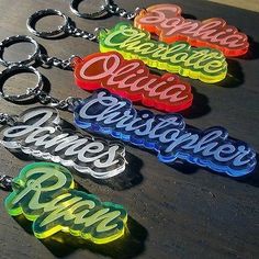 six key chains with the word game spelled in different colors and font on them, sitting on top of a wooden table