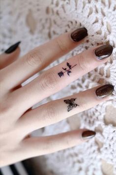 a woman's hand with a small butterfly tattoo on her left thumb and finger