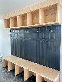 a wooden bench sitting in the middle of a room next to a wall filled with lockers